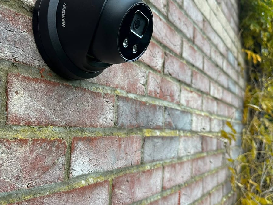 Black Hikvision turret camera mounted on a brick wall