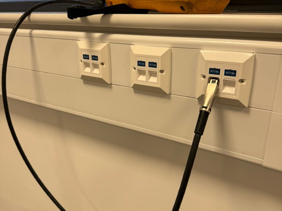Fluke tester connected to a labelled outlet in dado trunking