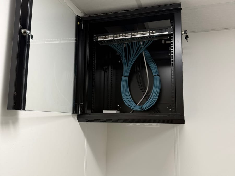 Wall-mounted data cabinet with an Excel patch panel and neatly looped cabling