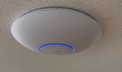 UniFi wireless access point installed on an office ceiling
