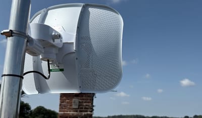 Ubiquiti LiteBeam point-to-point antenna on a farmhouse roof overlooking fields